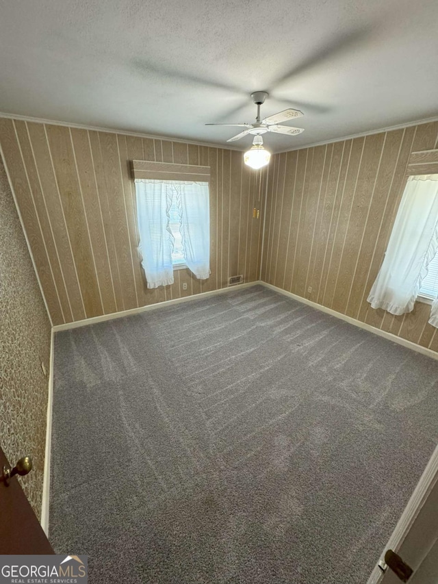 carpeted spare room with a textured ceiling, a ceiling fan, and baseboards