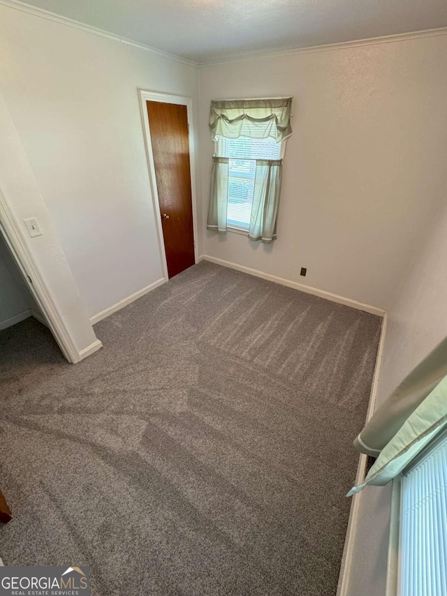 unfurnished bedroom with baseboards, dark colored carpet, and crown molding