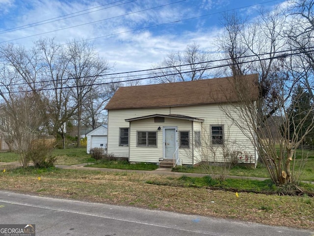 bungalow-style home with entry steps, a garage, and roof with shingles