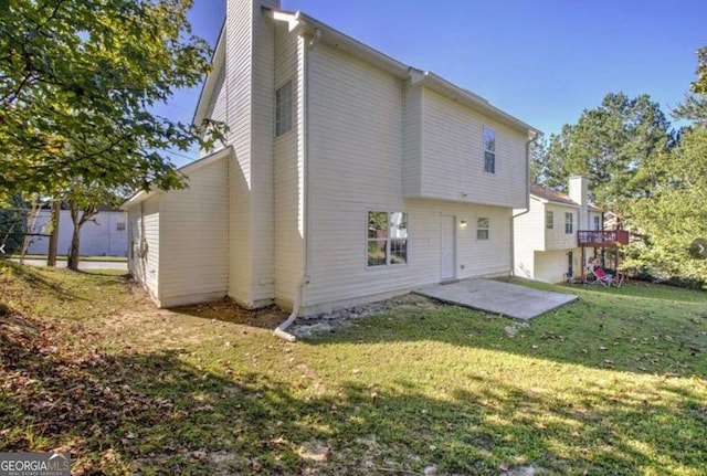 rear view of house featuring a lawn, a chimney, and a patio area