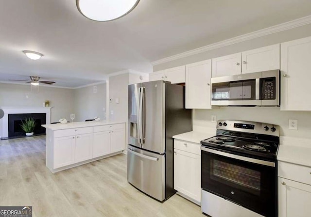 kitchen featuring appliances with stainless steel finishes, ornamental molding, a fireplace, and white cabinetry