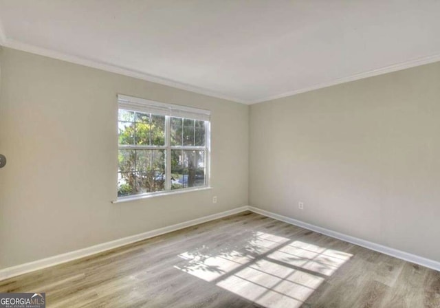 empty room with baseboards, wood finished floors, and crown molding