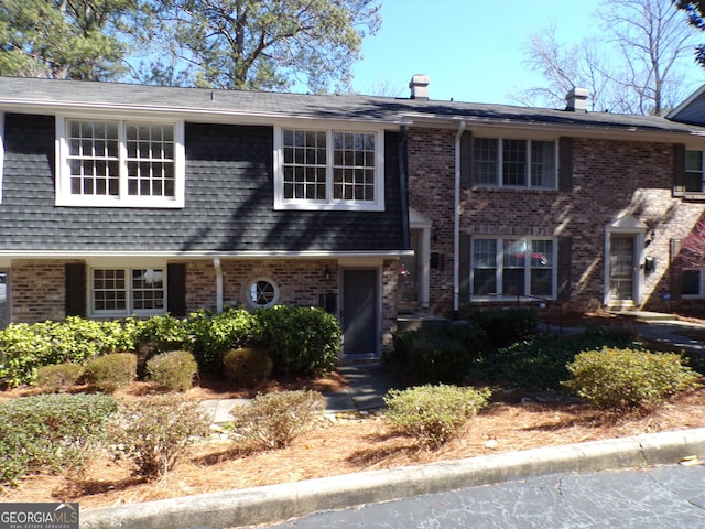 view of front facade with brick siding and a shingled roof