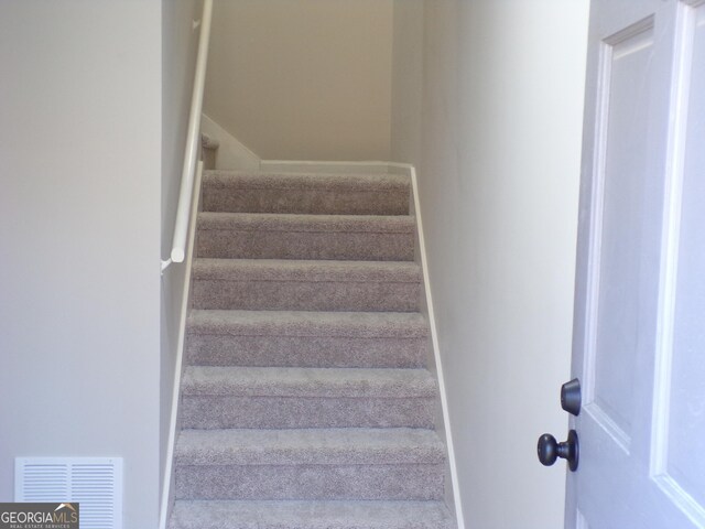 stairway with baseboards and visible vents