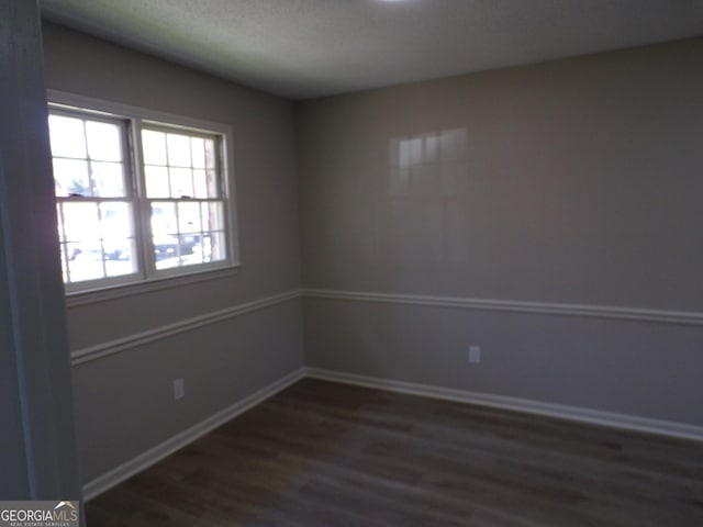 empty room featuring dark wood-type flooring and baseboards