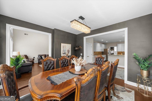 dining space with dark wood-style flooring, visible vents, and baseboards