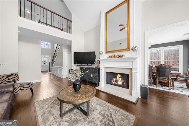 living room with plenty of natural light, stairs, hardwood / wood-style floors, and a glass covered fireplace