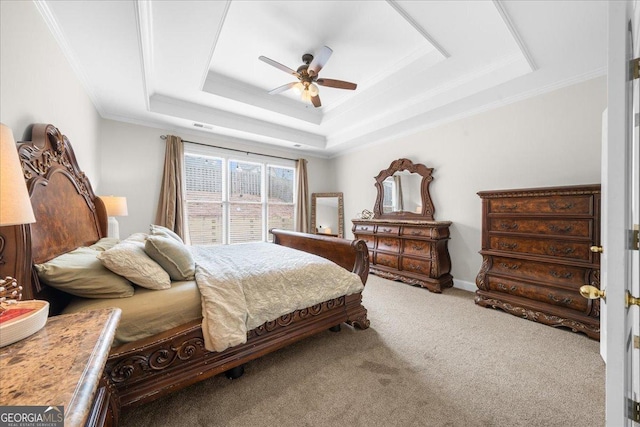 bedroom with baseboards, ceiling fan, ornamental molding, a tray ceiling, and carpet flooring