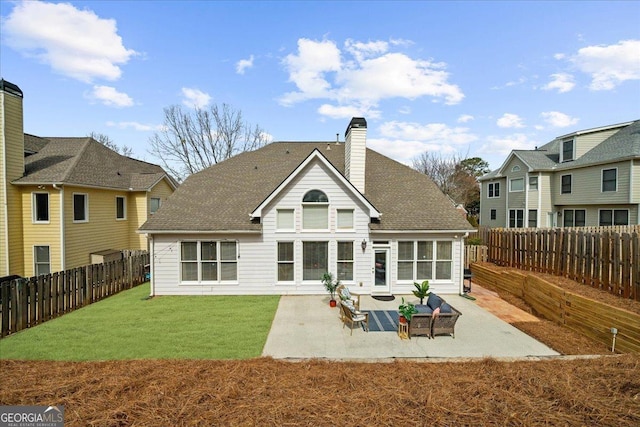 back of house with a chimney, a lawn, a patio area, and a fenced backyard