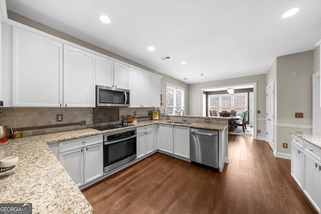 kitchen with dark wood finished floors, visible vents, appliances with stainless steel finishes, white cabinetry, and a sink