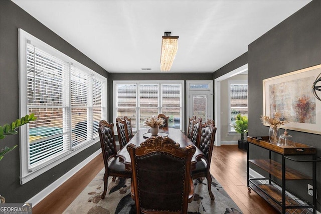 dining room featuring visible vents, plenty of natural light, baseboards, and wood finished floors