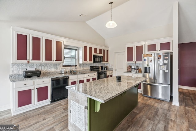 kitchen with wood finished floors, a kitchen island, a sink, black appliances, and vaulted ceiling