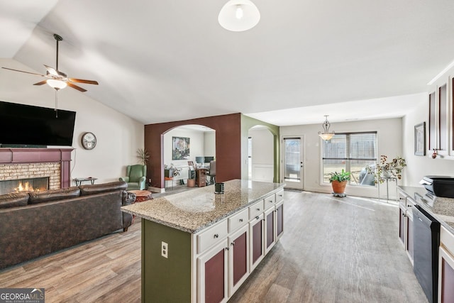 kitchen featuring a fireplace, arched walkways, light wood-style floors, dishwasher, and open floor plan