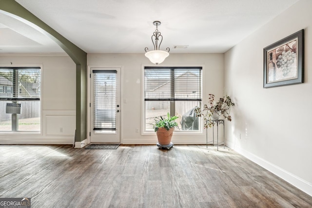 entrance foyer featuring visible vents, wood finished floors, arched walkways, and baseboards