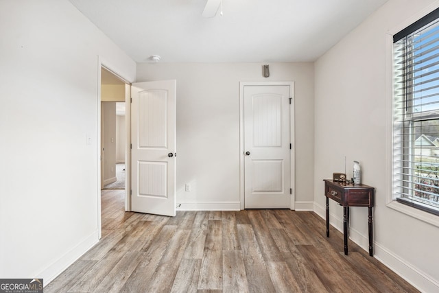 bedroom featuring multiple windows, baseboards, and wood finished floors