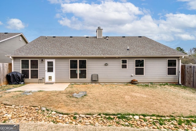 back of property featuring a fenced backyard, a chimney, a shingled roof, and a patio