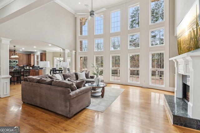 living area with a high end fireplace, arched walkways, crown molding, and ornate columns