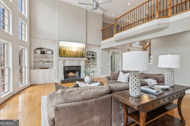 living area with a premium fireplace, stairway, built in shelves, and wood finished floors