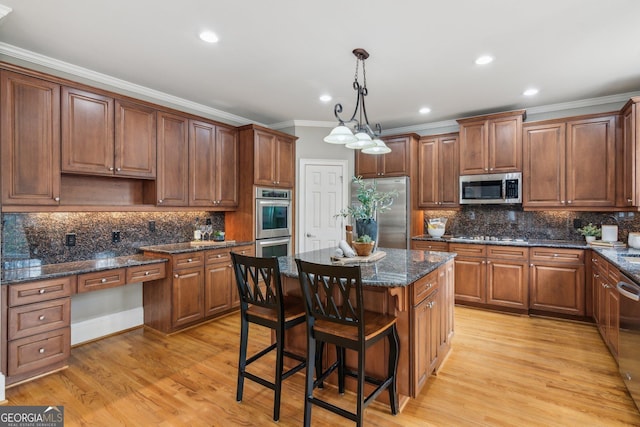 kitchen featuring light wood finished floors, ornamental molding, stainless steel appliances, backsplash, and a center island