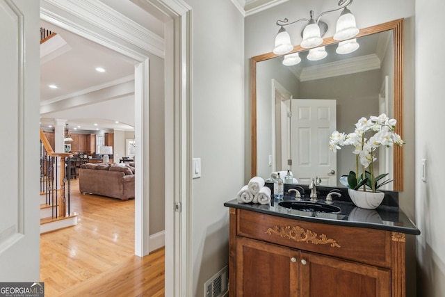 bathroom with vanity, wood finished floors, visible vents, baseboards, and crown molding