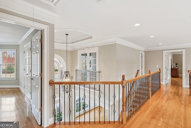 corridor with attic access, wood finished floors, an upstairs landing, and ornamental molding