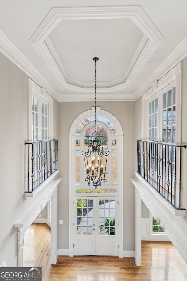 foyer featuring a notable chandelier, french doors, a tray ceiling, and wood finished floors