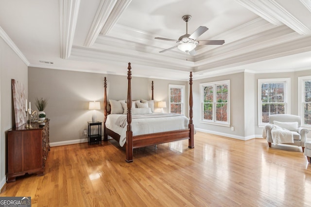 bedroom featuring light wood-type flooring, visible vents, a tray ceiling, crown molding, and baseboards