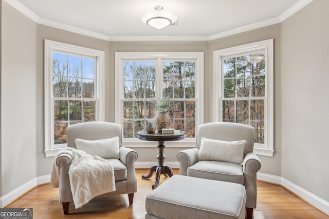 living area with crown molding, light wood-style flooring, and baseboards