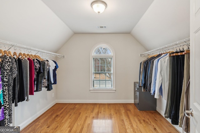 walk in closet with lofted ceiling, light wood-style flooring, and visible vents