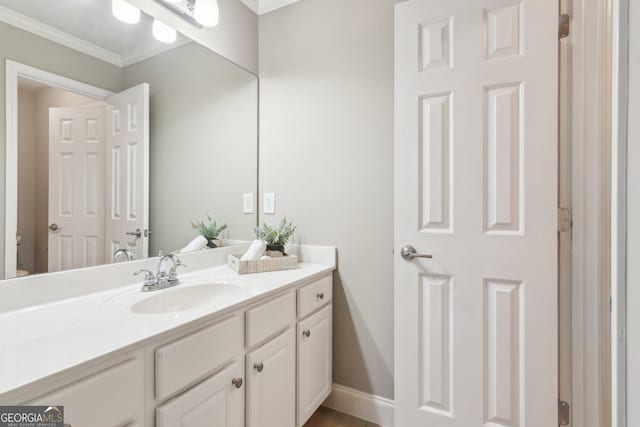 bathroom featuring baseboards, ornamental molding, and vanity