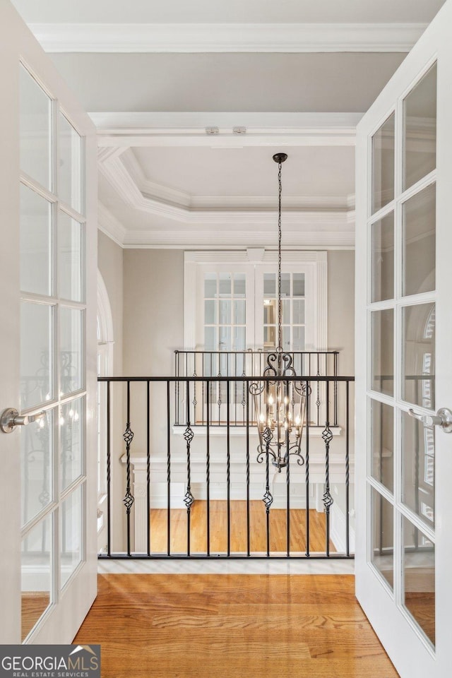 hall with ornamental molding, wood finished floors, and a chandelier