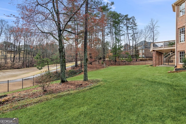 view of yard featuring a deck, stairway, and fence