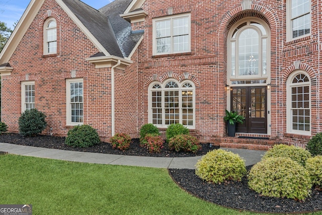 exterior space with french doors, brick siding, and a shingled roof