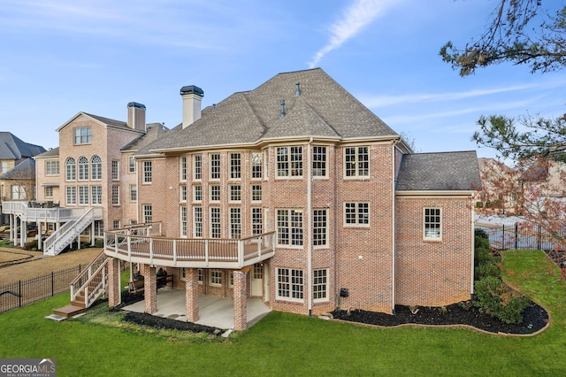 back of property with a yard, roof with shingles, brick siding, stairs, and a patio area