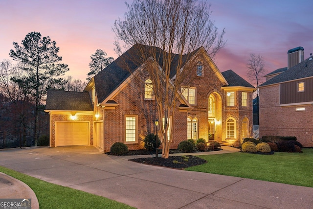 view of front of house featuring a garage, brick siding, driveway, and a yard