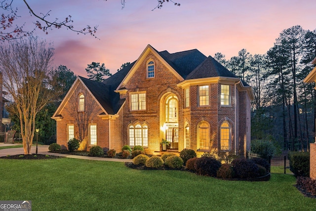 view of front of property featuring a yard, fence, and brick siding