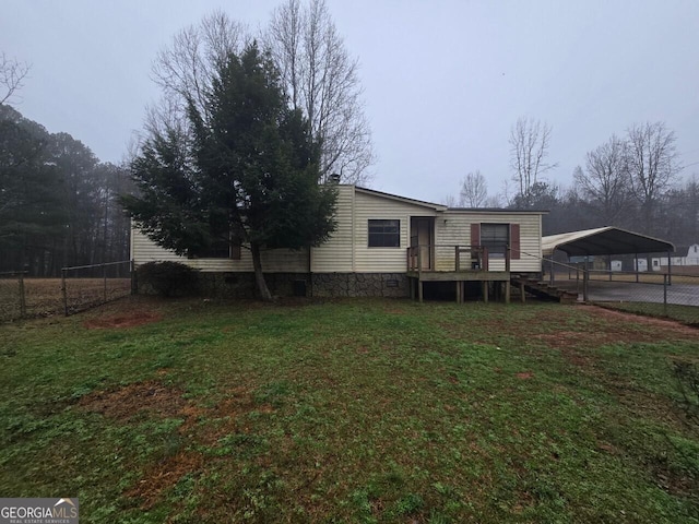 rear view of house with a lawn, fence, and a detached carport