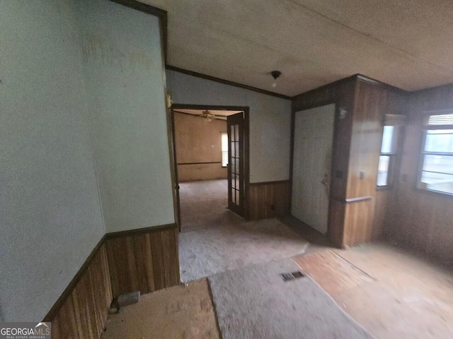 spare room with lofted ceiling, a wainscoted wall, wooden walls, and visible vents