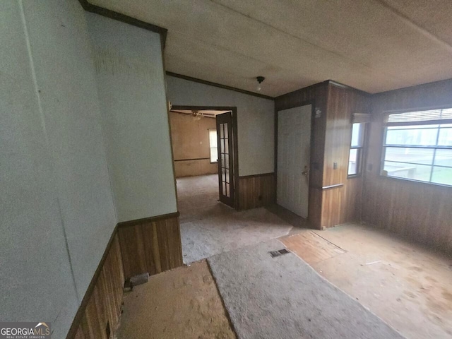 interior space featuring wood walls, a wainscoted wall, vaulted ceiling, and visible vents