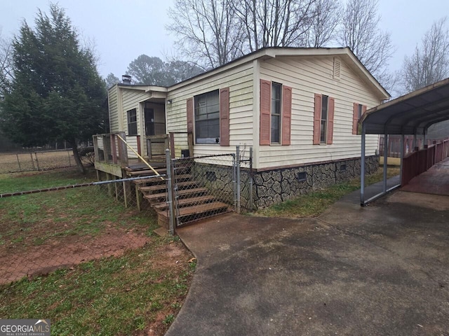 view of front facade with fence, driveway, crawl space, a wooden deck, and a detached carport