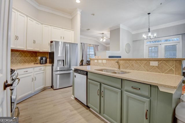 kitchen with white cabinets, stainless steel appliances, crown molding, and a sink