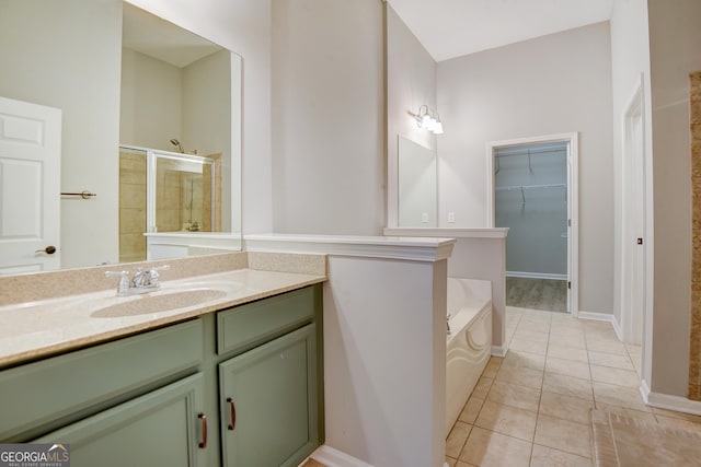 bathroom featuring a walk in closet, a stall shower, tile patterned flooring, a bath, and vanity