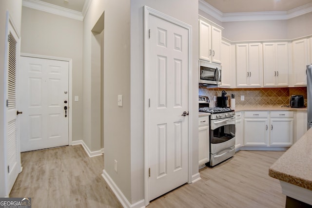 kitchen with white cabinets, light wood-style floors, appliances with stainless steel finishes, and ornamental molding