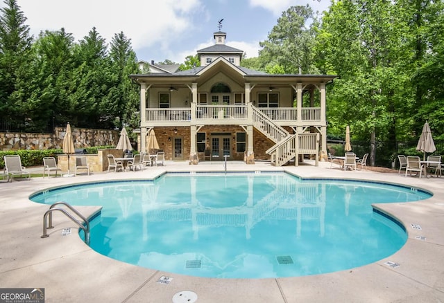 pool with fence, stairway, french doors, ceiling fan, and a patio area