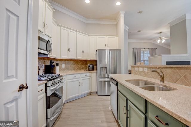 kitchen featuring green cabinetry, a sink, appliances with stainless steel finishes, white cabinetry, and crown molding