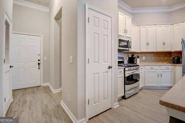 1910 Cedar Glenn Unit 4401, Atlanta, GA 30339 - kitchen with appliances with stainless steel finishes, light wood finished floors, white cabinetry, crown molding, and tasteful backsplash