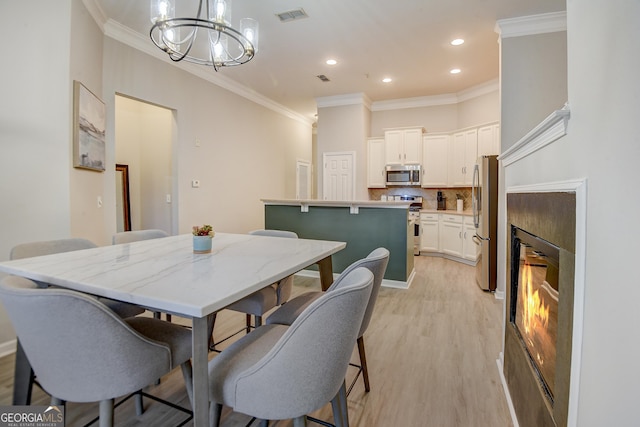 dining area with visible vents, an inviting chandelier, light wood-style flooring, and crown molding