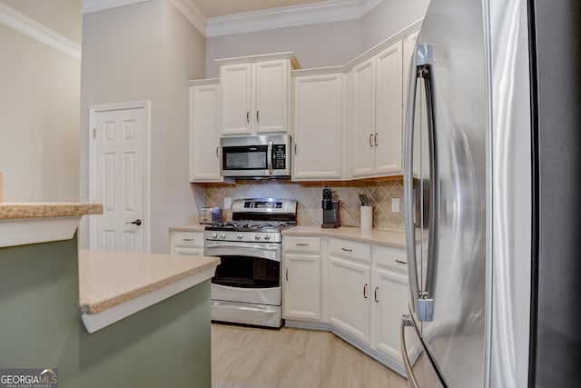 kitchen with white cabinets, ornamental molding, tasteful backsplash, and stainless steel appliances