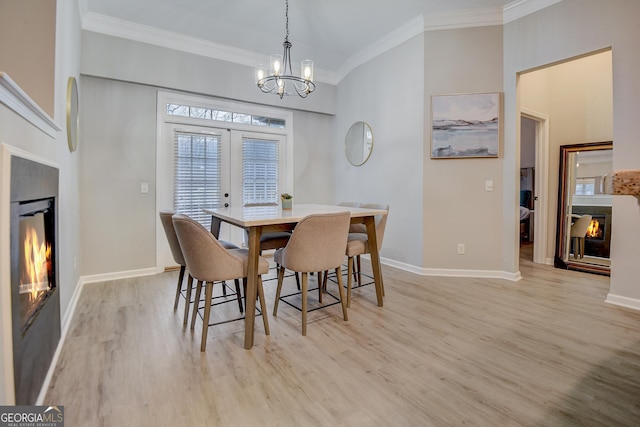 dining area with light wood-style flooring, a glass covered fireplace, and crown molding