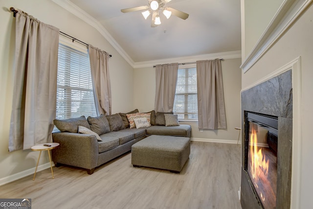 living area with baseboards, light wood finished floors, a high end fireplace, vaulted ceiling, and crown molding